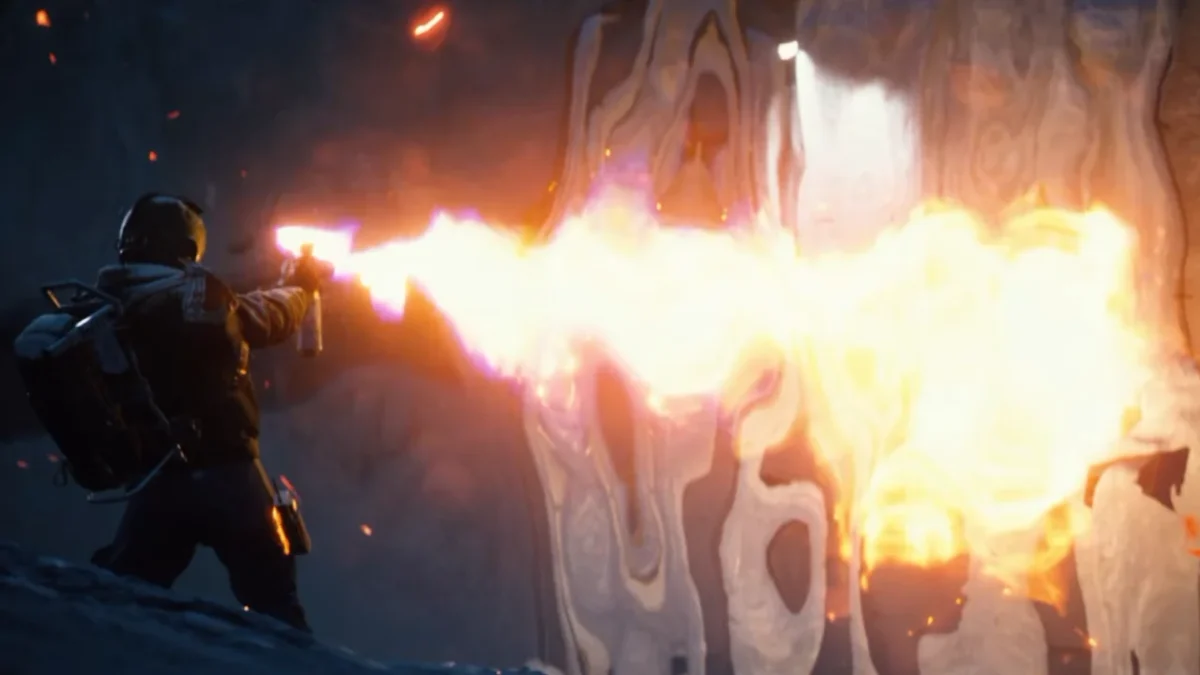 ARC Raiders character using a flamethrower against a wall in a dark, sci-fi environment.