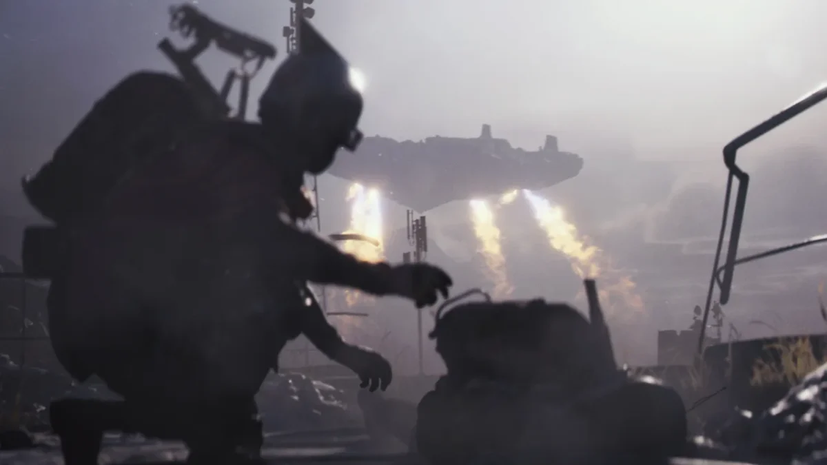 A Raider crouches over a bag in the foreground while the ARC Frigate hovers in the distance with its thrusters burning