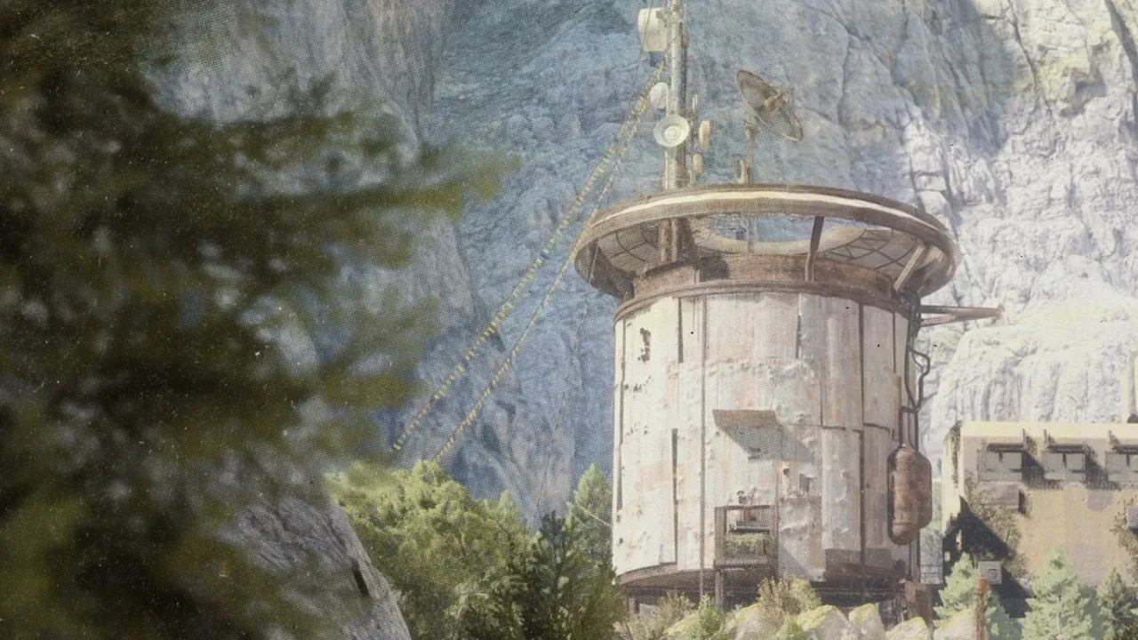 A weathered round tower building on a rocky cliffside among pine trees