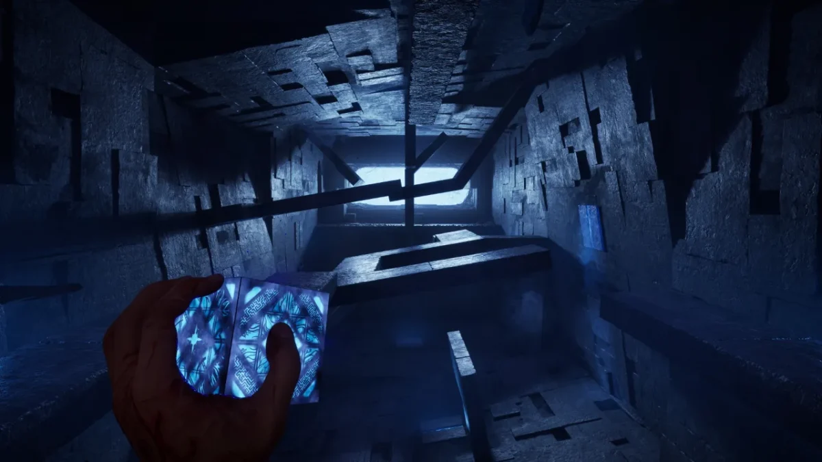 First-person view down a blue-lit stone Labyrinth corridor with the glowing puzzle box in hand in Hellraiser: Revival