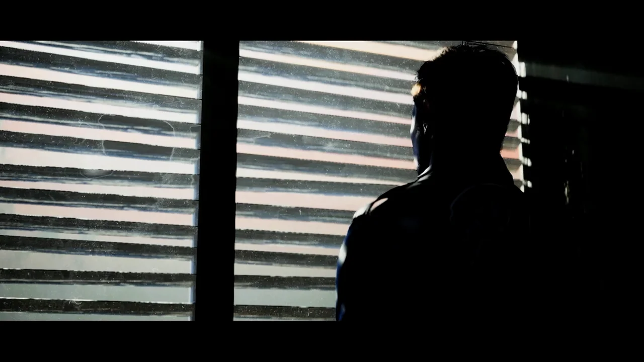 Aidan in silhouette at a window with blinds, from the Stay Human ending of Hellraiser: Revival